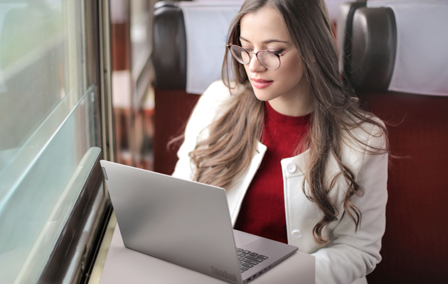 Alltid effektiva ThinkBooks Affärskvinna arbetar med hennes Lenovo ThinkBook under en tågresa