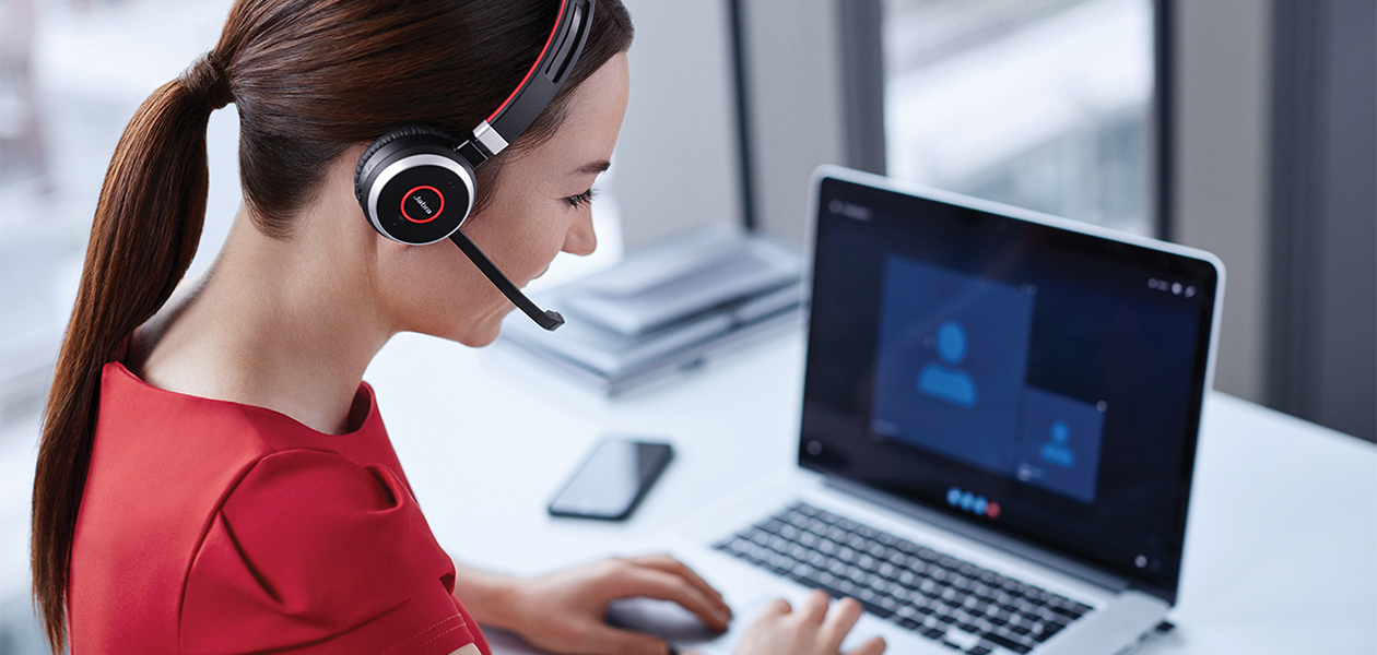 Jabra Evolve2 – en helt ny standard for hodetelefoner Kvinne sitter med Jabra on-ear hodetelefoner foran en bærbar PC