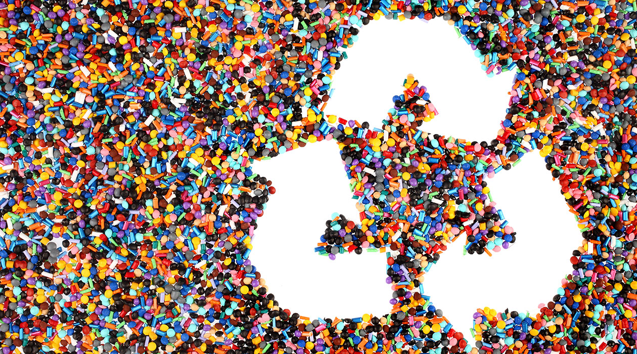 Resirkulert plast er mest klimavennlig Hvit resirkuleringslogo av tre piler som danner en trekant og peker i sirkel, på en bakgrunn av multifargede plastpellets
