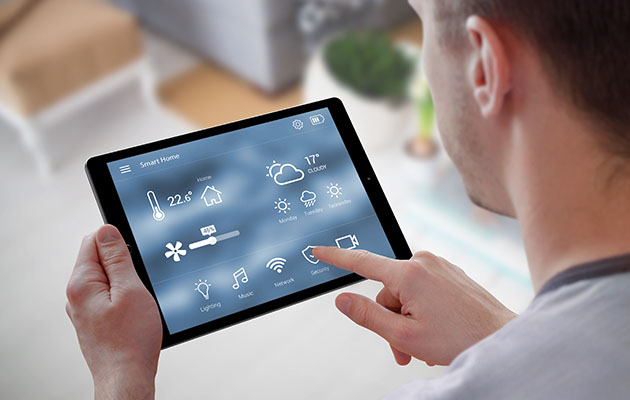 Kontroller varmen og energiforbruket ditt. Hender som holder et tablet med smart apper.