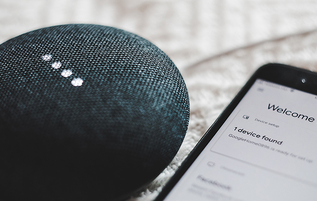 En Google Home Mini-høyttaler ved siden av en smarttelefon