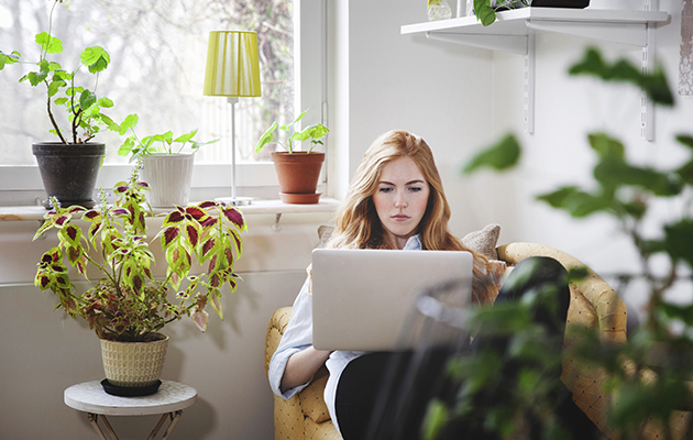 Pålitelig nett med mesh En kvinne sitter i sofaen med en bærbar PC i fanget