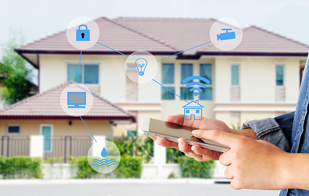 Ta styring over hele hjemmet Hender som holder en smarttelefon foran et stort hus.