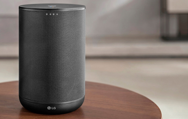 LG AI ThinQ smarthøyttaler støtter Google Assistant En sort høyttaler med LG-logo som står på et rundt bord