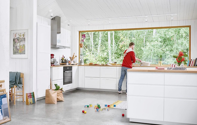 Ha full kontroll på komfyren, selv om du ikke er på kjøkkenet En mann tilbereder middag på kjøkkenet ved hjelp av en Electrolux smart ovn.