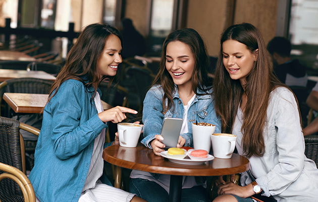 Personaliser det du lærer Tre damer på en kaffe som ser på en smarttelefon