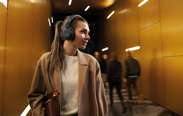 Aktiv støydemping er en teknologi hvor hodetelefonene sender ut motsignaler mot støy i omgivelsene slik at denne kanselleres ut Kvinne med Jabra Elite 85h