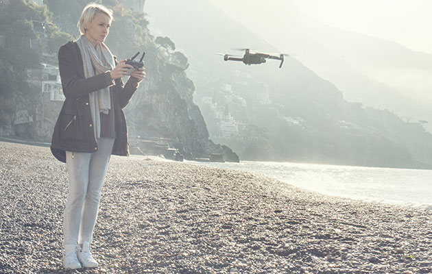 Se verden fra en annen vinkel En dame som flyr en drone over en strand