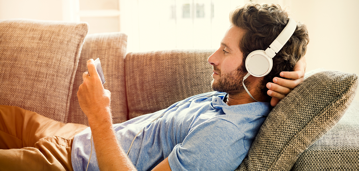 Finn den beste mobilen til å se film og serier på Mann ligger på sofa og ser på mobilen