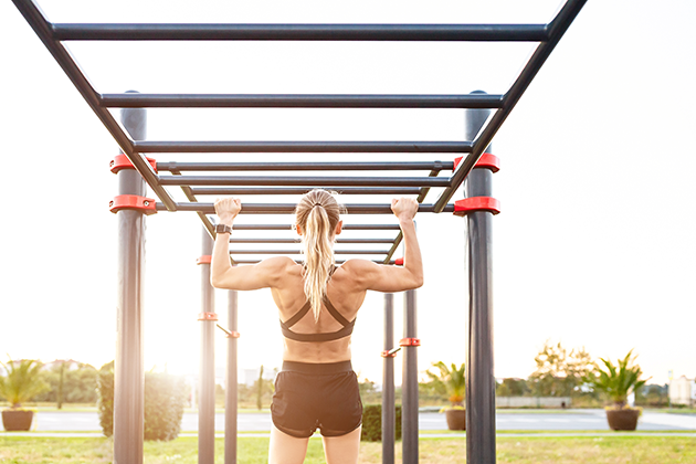 Velg en sportsklokke som holder hele treningsøkten Kvinne tar en pull-up med en sportsklokke på håndleddet