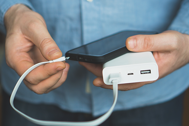 Du kan enkelt lade opp telefonen med en powerbank Person holder mobiltelefon og powerbank
