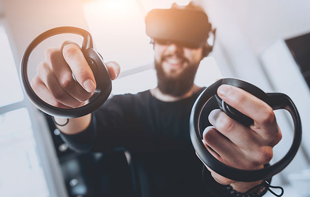 VR-spill er gøy En mann med skjegg har VR-briller på og to VR-kontrollere I hendene