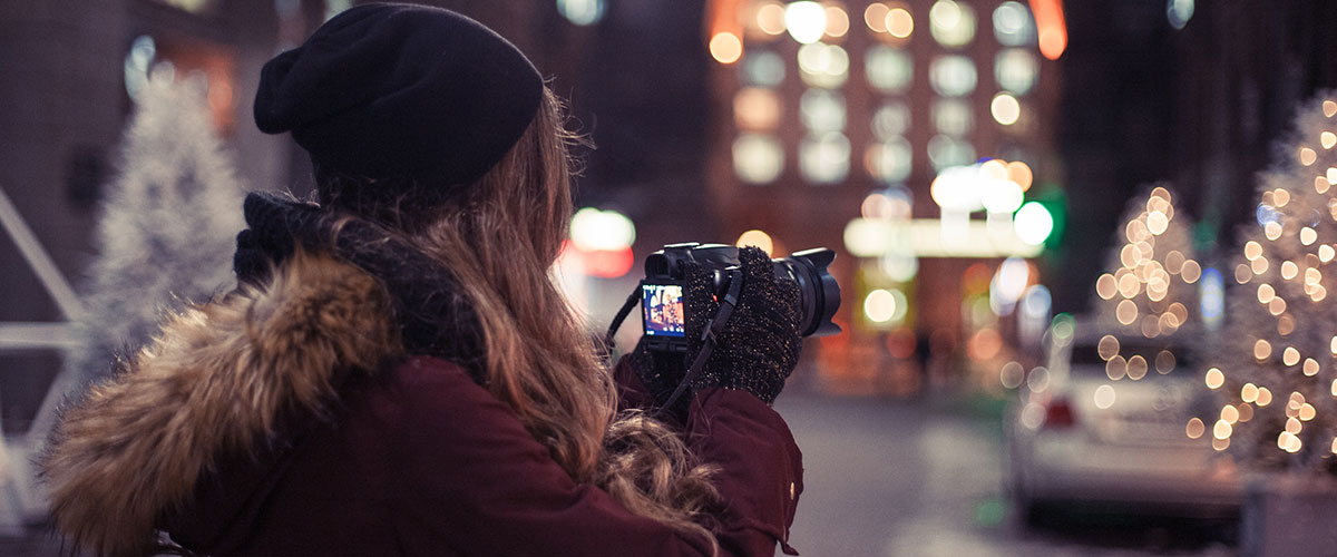 Månedens fotodeal En laghåret fotograf ses bakfra mens vedkommende fotograferer trær med julebelysning på