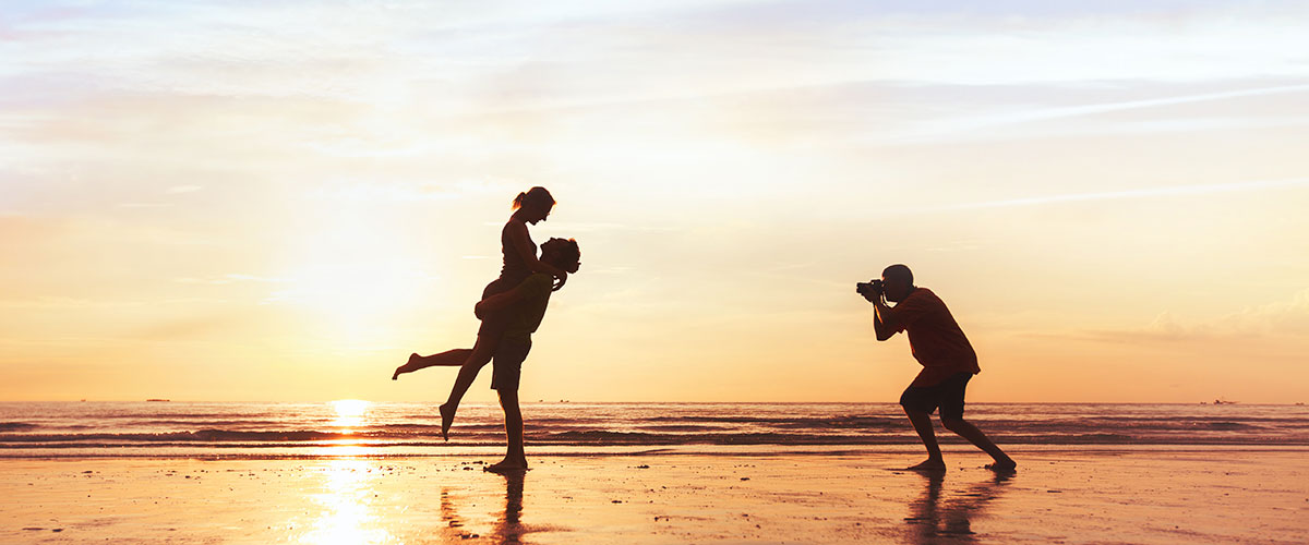 Månedens fotodeal Strand i solnedgang med silhuetten av en fotograf som fotograferer et dansende par
