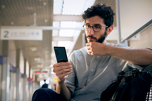 Sony Xperia 5 har et kompakt design som passer godt i hånden Mann sitter med Sony Xperia 5 i hånden