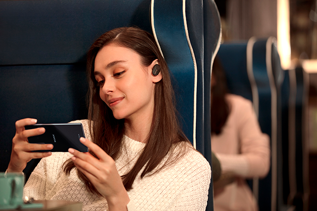 Sony Xperia 5 har Dolby Atmos-lyd Kvinne på toget med Sony Xperia 5 og høretelefoner