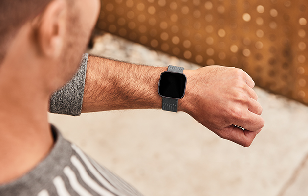 Fitbit Versa 2 er vannbestandig ned til 50 m, så du kan trygt bruke den i bassenget, i dusjen, på stranda og mer Mann med fokus på armen med Versa 2
