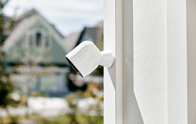 Arlo Pro 3 passer på hjemmet ditt, slik at du trygt kan gjøre andre ting. Arlo Pro 3 på vegg med hus i bakgrunnen