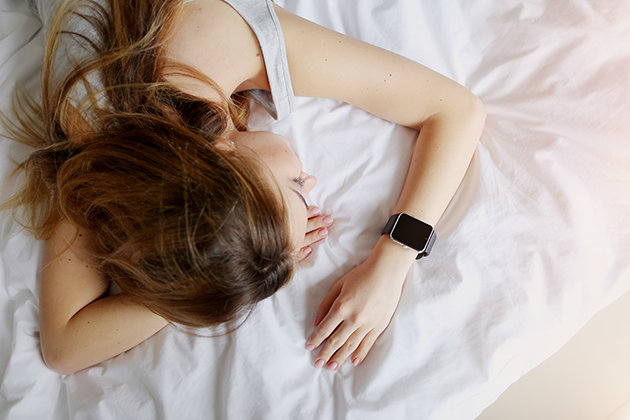 Hvordan måles søvnen din? Kvinne sover med smartklokke på