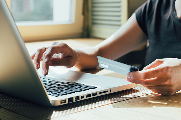 Prisen på en ny telefon er viktig Person sitter foran datamaskin med kredittkort i hånden