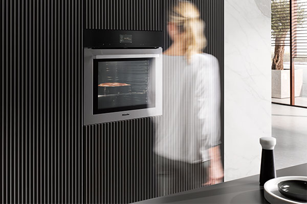 MotionReact – samspill med ovnen ved hjelp av bevegelse Miele ovn Generasjon 7000 med MotionReact passeres av kvinne