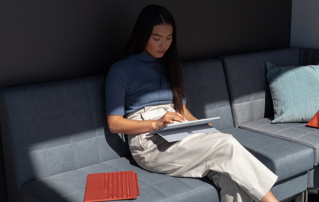 Bruk Surface Pro 7 slik du ønsker Kvinne som sitter i en sofa og bruker Surface Pro 7
