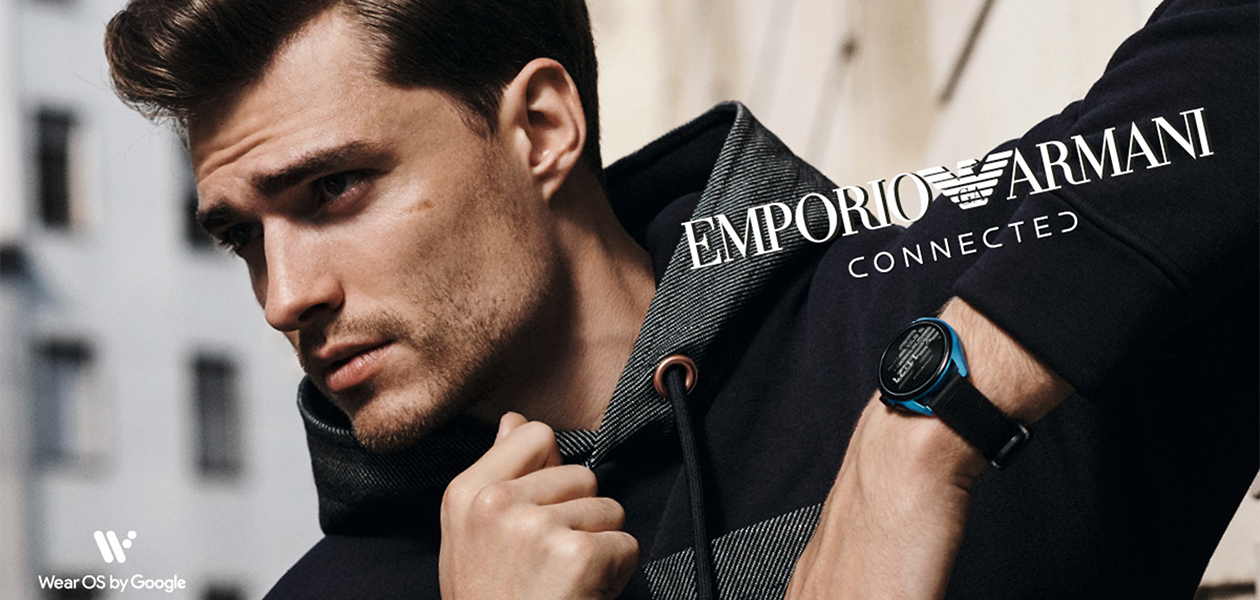 Emporio Armani Gen 5 Mann lener seg mot en vegg med en Emporio Armani-klokke rundt håndleddet