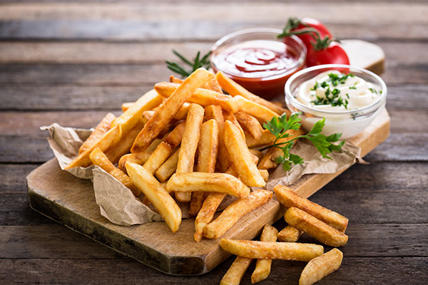 Lag mat ute Pommes frites, majones og ketchup på en skjærefjøl