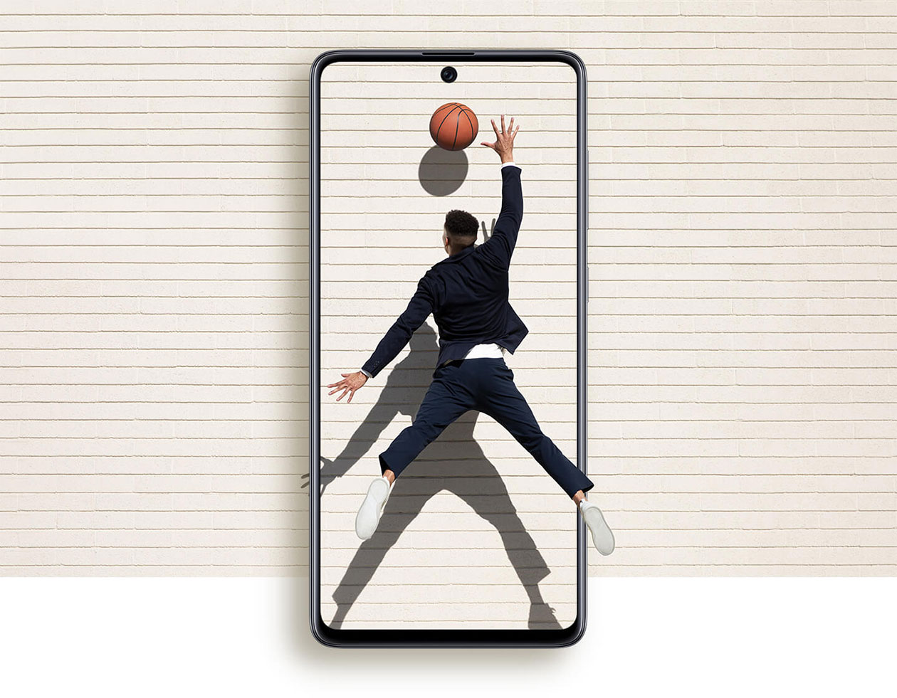 Opplev mer med en større skjerm Forstørret Samsung Galaxy A71 mobiltelefon og mann som strekker seg etter en basketball