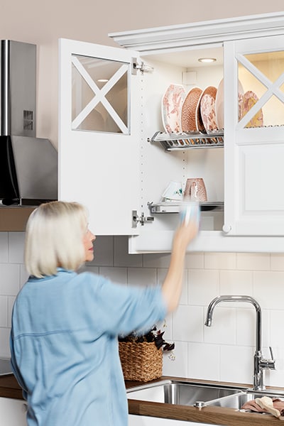 En kvinne tar en kopp ut fra et kjøkkenskap