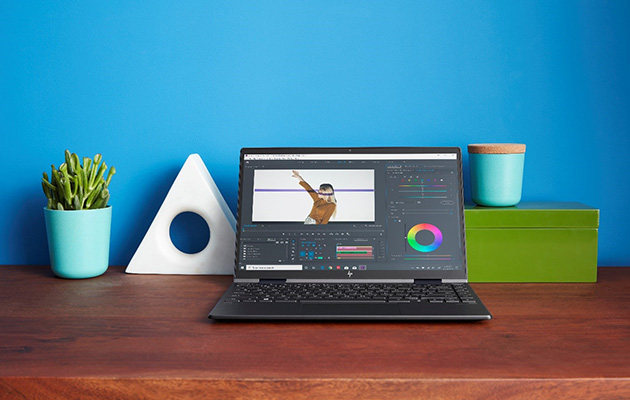 HP Envy x360 - mektig lydopplevelse HP Envy x360 på et skrivbord framfor en blå vegg