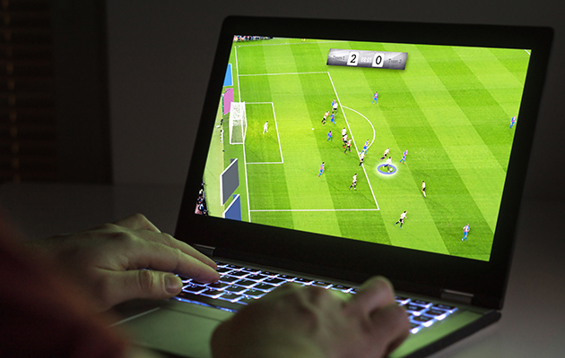 Bakbelyst tastatur Person spiller fotballspill på en PC med bakbelyst tastatur