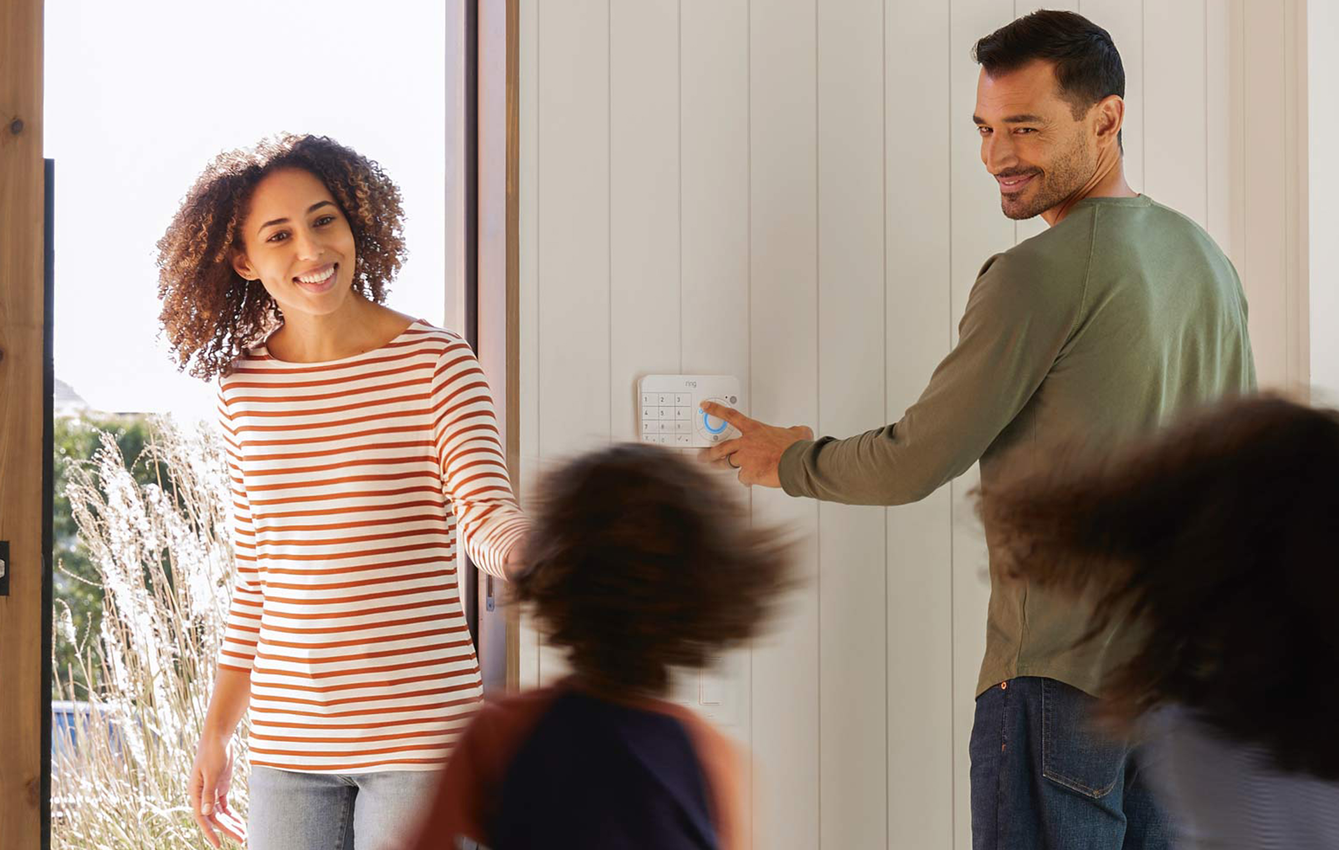 Ring Alarm Far som trykker på alarmpanel med familien rundt