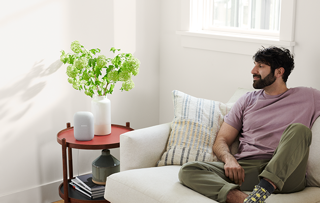 Nest Audio fungerer med andre Nest-høyttalere og -skjermer samt Chromecast-kompatible enheter Google Nest Audio og mann i sofa