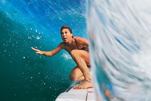 En kvinne på surfebrett inni en bølge