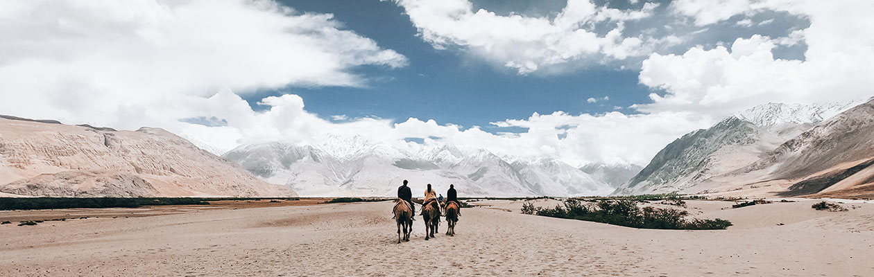 Landskapsbilde med ørken og fjell, tre silhuetter av mennesker sees i midten av bildet