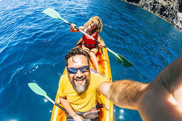 Et middelaldrende par på surfebrett tar selfie med et actionckamera