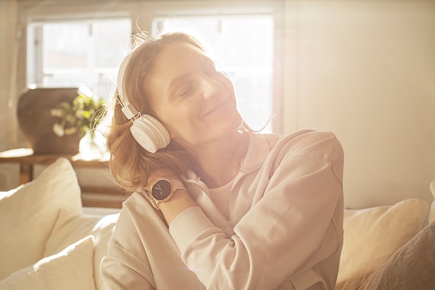 En kvinne med hodetelefoner som hører på musikk fra sin Polar Ignite 2