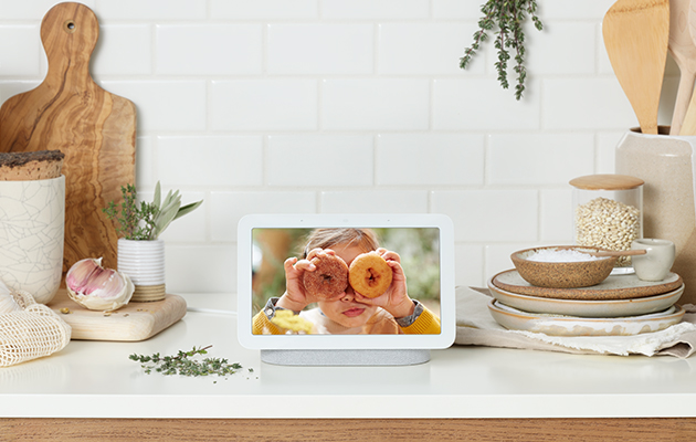 Skjermen viser automatisk de beste bildene dine fra Google Foto, slik at du alltid har favorittene dine i bakgrunnen Jente med smultringer foran øynene på Google Nest Hub