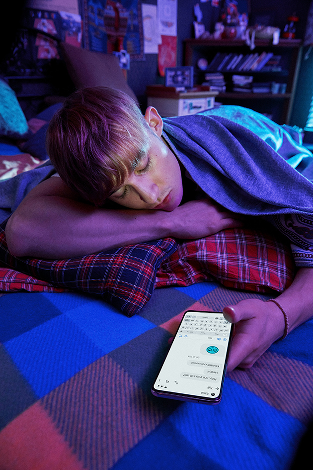 OnePlus Nord CE 5G med lysende skjerm i hånden på en sovende mann