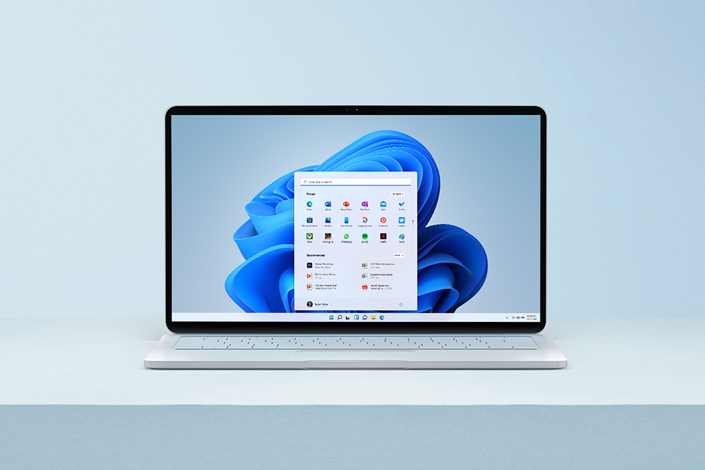 Windows 11 Windows 11-PC på et hvitt bord med hjemskjermen på PC-en oppe