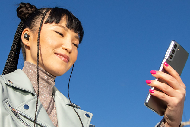 Beats Studio Buds gir en større trådløs rekkevidde og færre avbrudd Beats Studio øretelefoner i ørene på kvinne som holder mobil i hånden