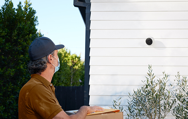 Nest Cam går på batteri og er værbestandig Nest Cam på vegg med mann