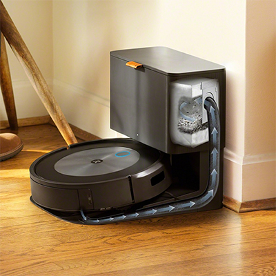 Roomba® j7/Roomba® j7+ -robotstøvsuger En svart robotstøvsuger parkert ved støvbeholderen