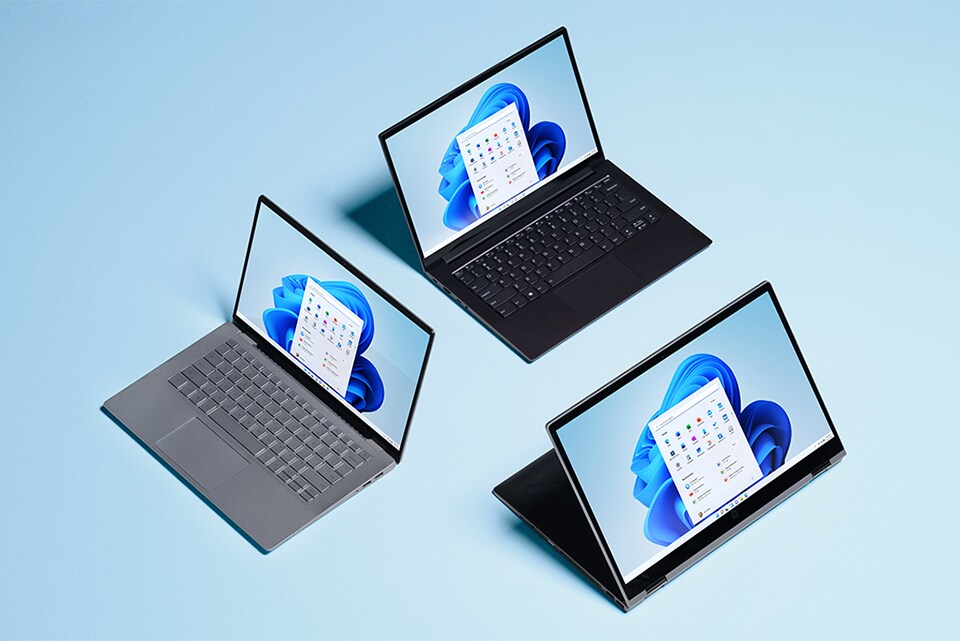 Tre Windows 11-laptoper foran blå bakgrunn