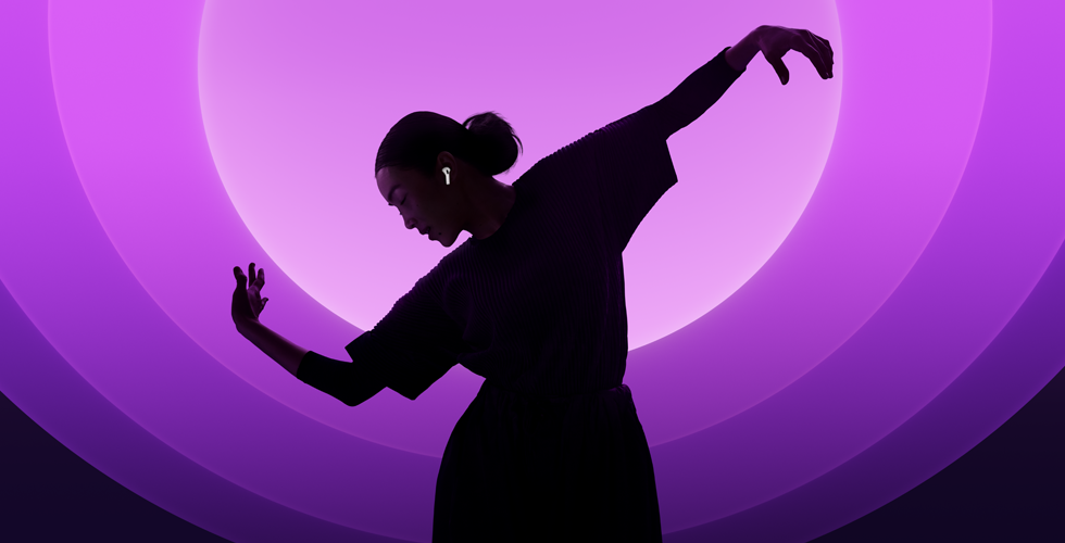 En person som bruker AirPods 5 og danser foran flerfarget bakgrunn