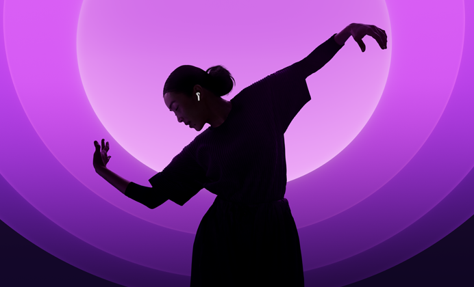 En person som bruker AirPods 5 og danser foran flerfarget bakgrunn