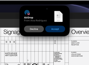 Dynamic Island vises på skjermen med en AirDrop-forespørsel i et lite vindu over en åpen Adobe Acrobat-fil