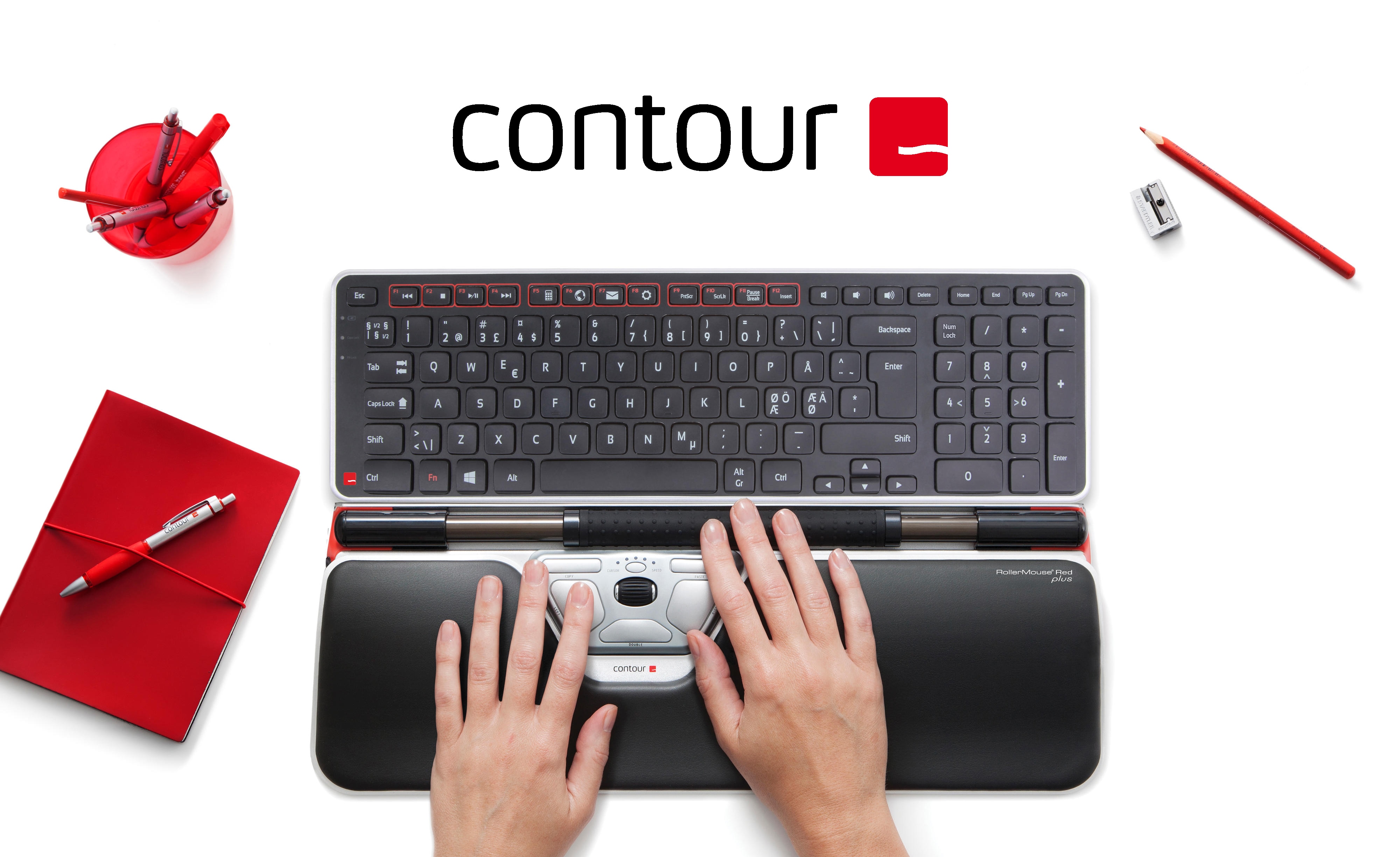 Contour tilbehør på et hvitt bord ved siden av en dataskjerm og rødt kontorrekvisita