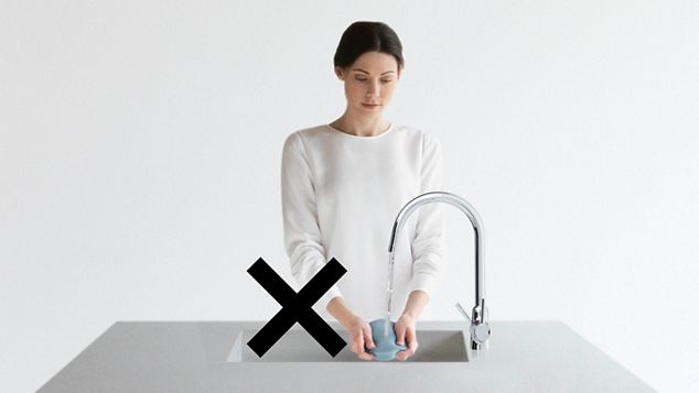 En kvinne som vasker et filter i en vask og et stort sort kors 